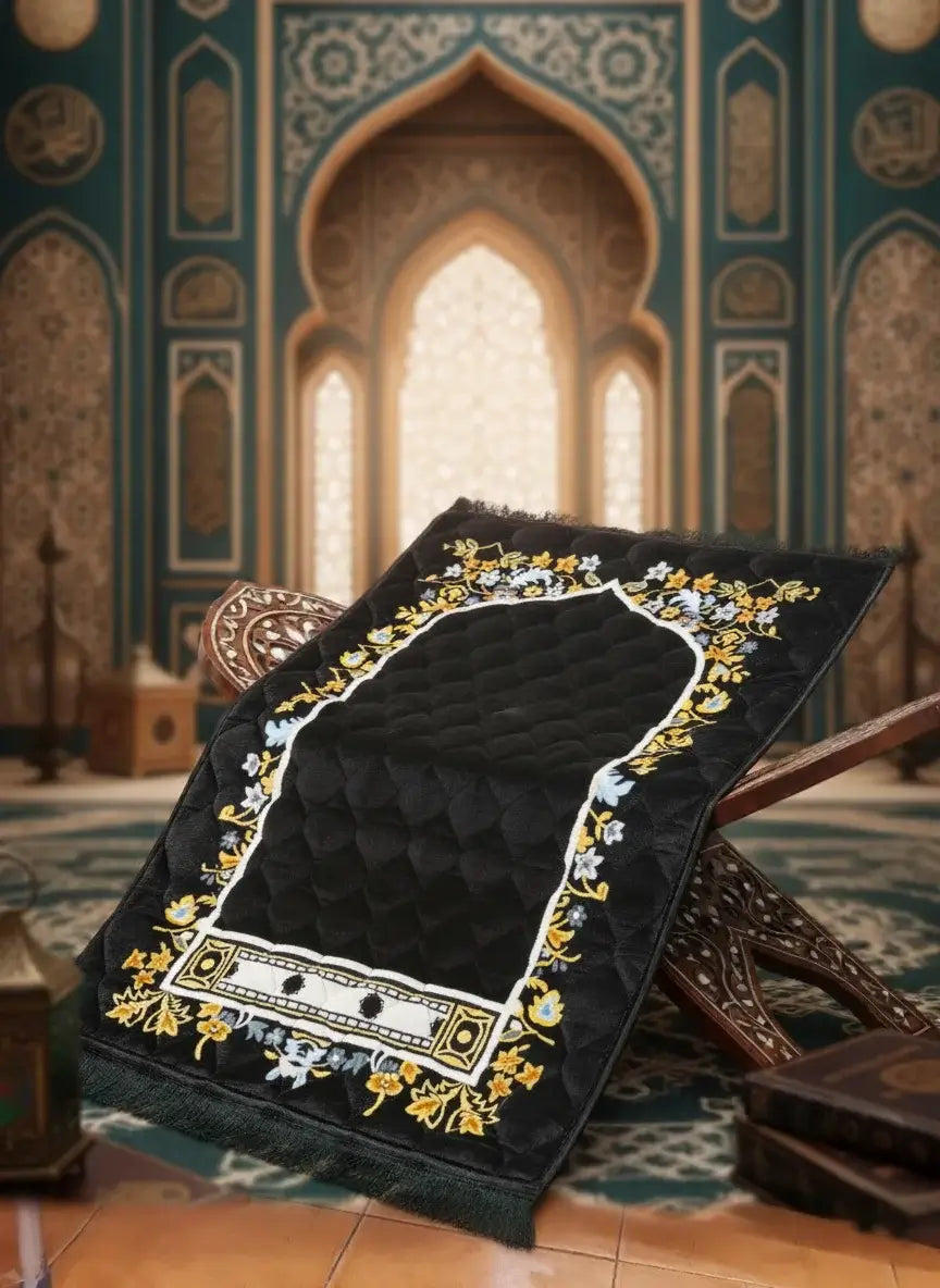 Decorative black prayer mat with gold embroidery on a patterned floor.
